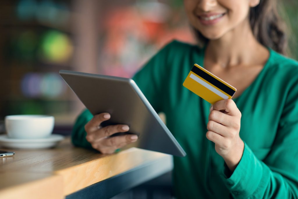 Unrecognizable young lady banking online, using digital tablet at cafe