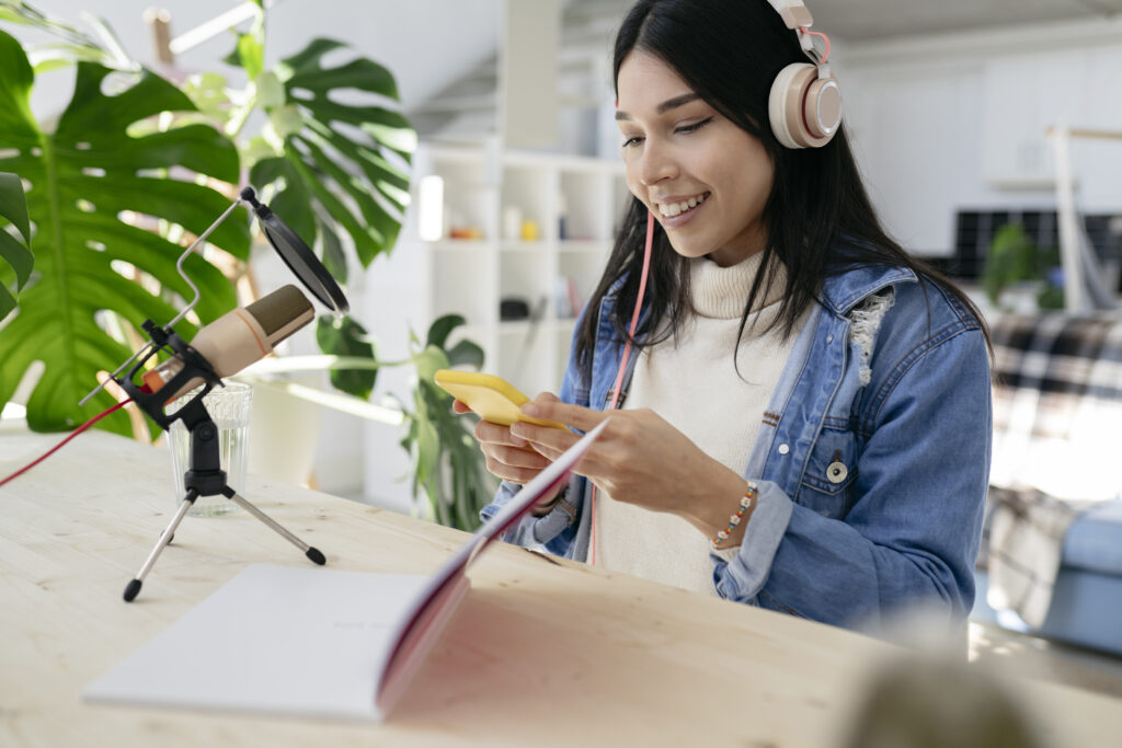 pretty latin hispanic woman doing a podcast with microphone notebook smartphone at home