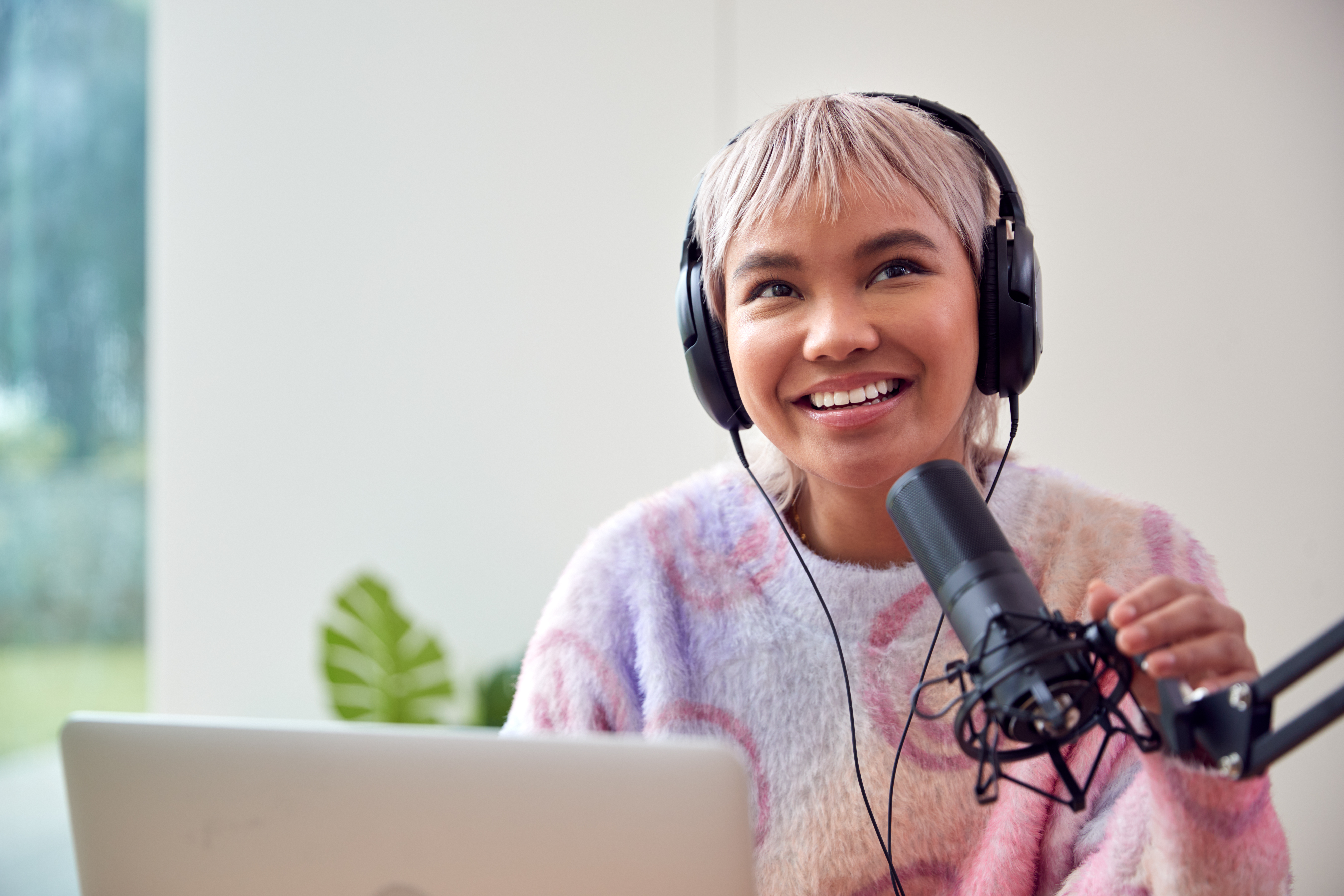 Woman Recording Podcast Or Broadcasting On Radio In Studio At Home With Laptop